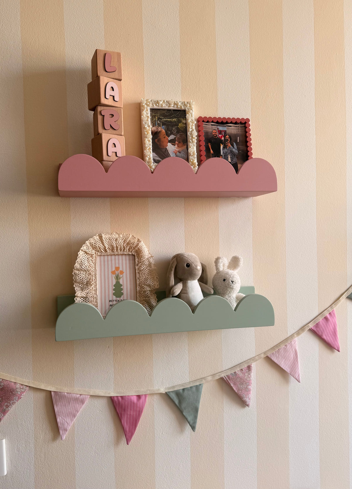 Pink and sage green cloud shelves styled with personalized wooden name blocks, framed prints and nursery accessories.