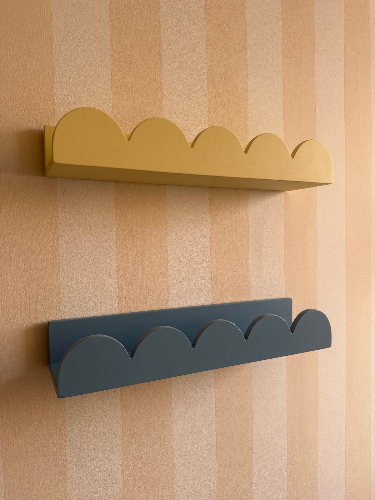 Yellow and dusty blue cloud-shaped wall shelves shown from the side, highlighting their depth and curved design.