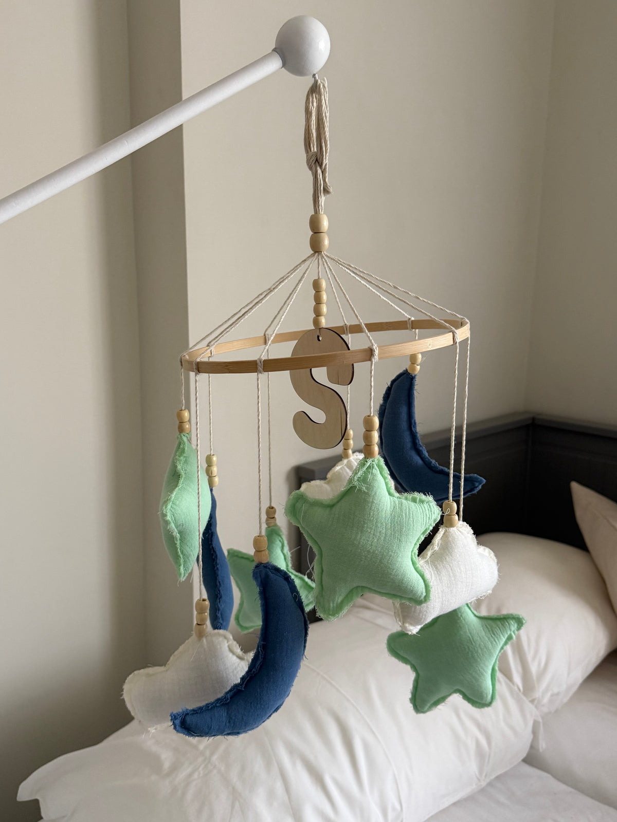 Personalized blue and mint moon and stars nursery mobile with soft fabric shapes suspended from a wooden hoop